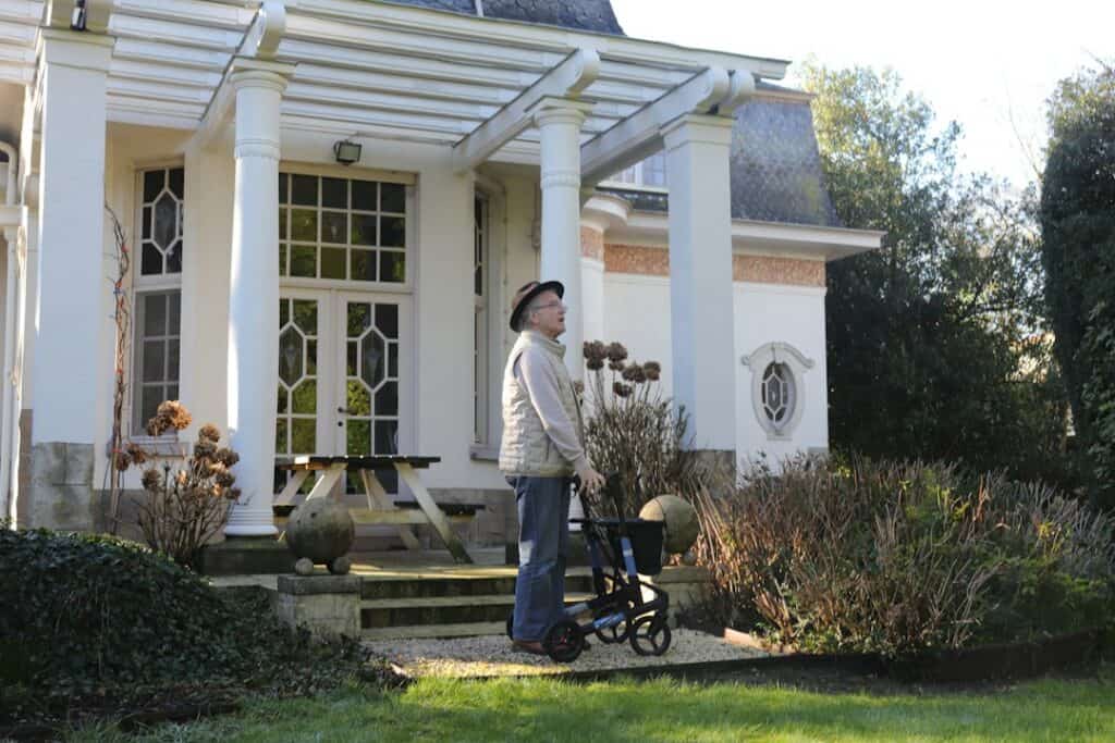 Senior using a sturdy walker outside a home - choosing a heavy-duty bariatric walker