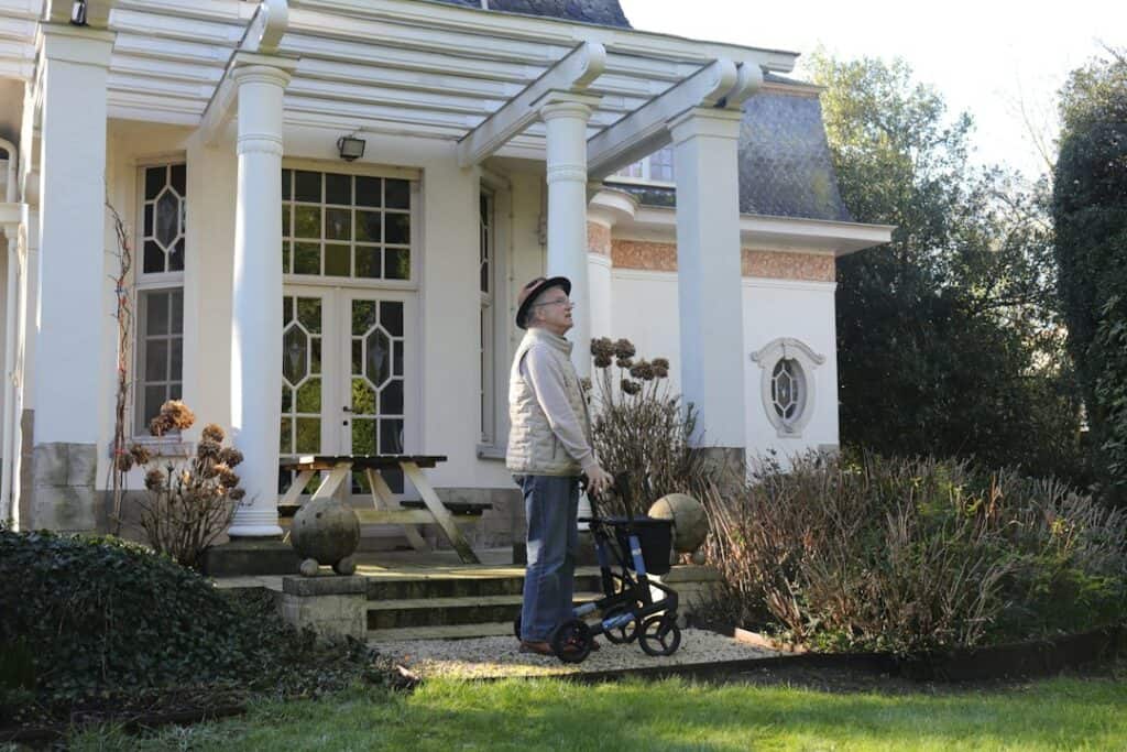 Senior with a compact folding walker outside the house, ready for a car trip