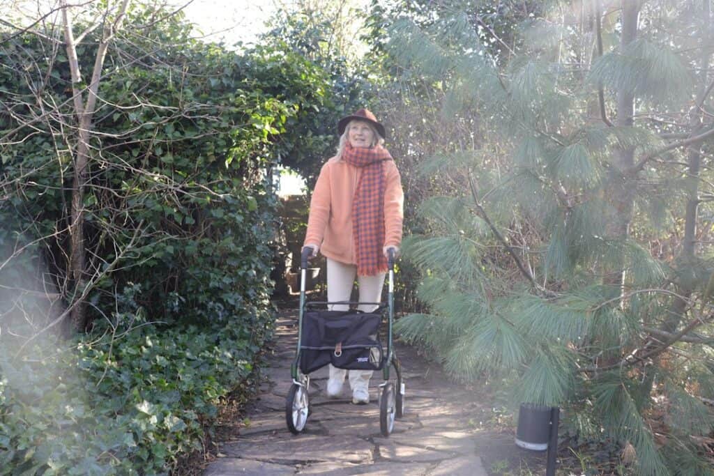 Older woman walking with a walker on a garden path