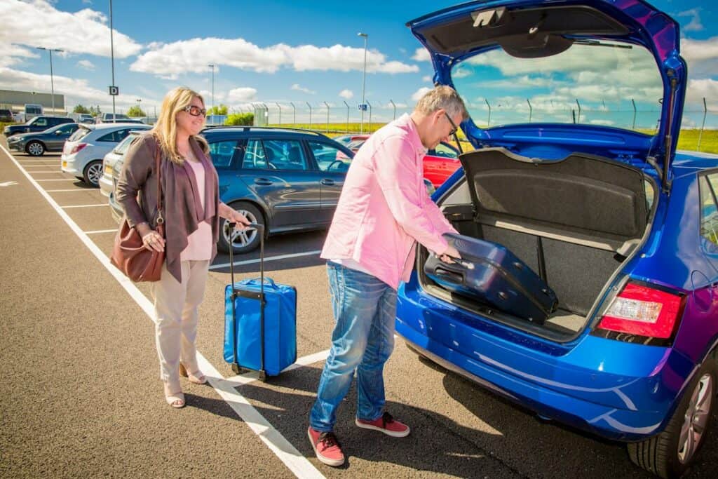 Couple loading luggage into a car trunk before a trip - planning space for a compact folding travel walker