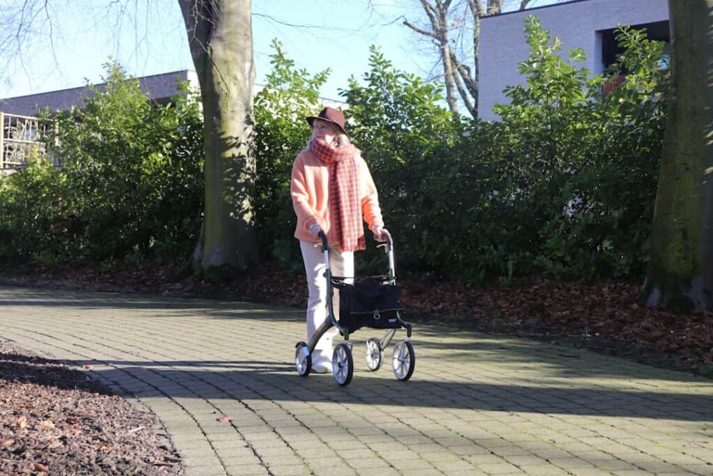 Senior walking outdoors with a four-wheel rollator walker