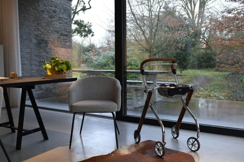 Walker parked beside a chair near a bright window at home