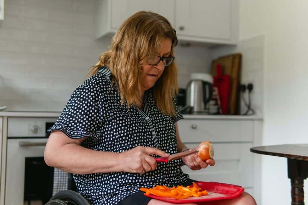 Older woman preparing food at a kitchen table, the kind of daily task a walker tray helps with