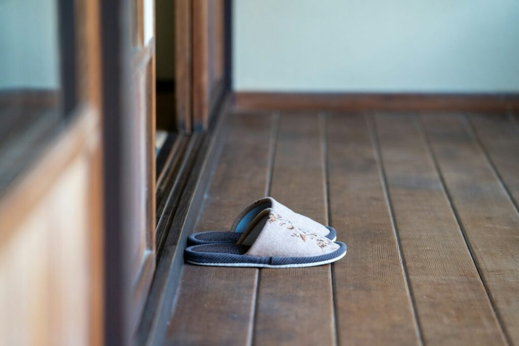 Best Non-Slip Slippers & Shoes for Elderly: 6 Picks for Fall Prevention 1 A slipper on a wooden floor - choosing non-slip slippers for elderly fall prevention